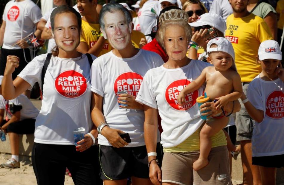 Fans wearing masks depicting members of Britain's royal family wait for Prince Harry to arrive at...