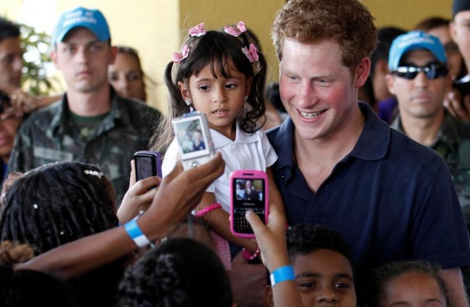 Prince Harry holds Mayara Pereira, 3, as he visits the occupied community of Complexo do Alemao...