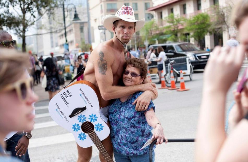 'Naked Cowboy', the guitarist known for parading in New York's Times Square, hugs a woman during...