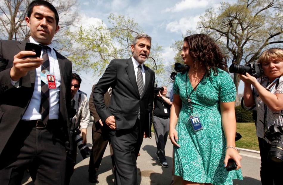 Actor George Clooney is escorted to the microphones to speak to reporters after his meeting with...