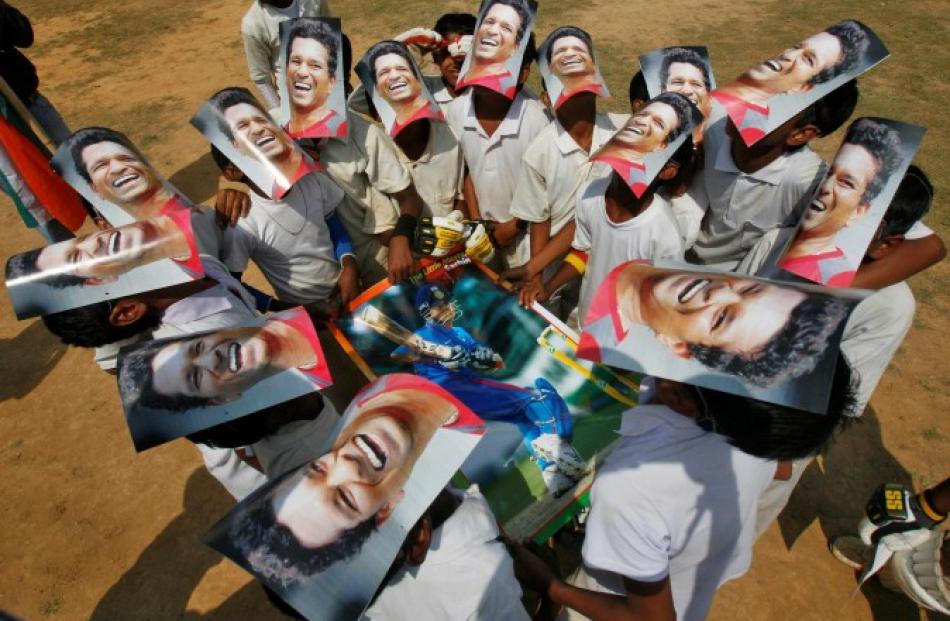 Boys from a local cricket academy wearing masks of Indian cricketer Sachin Tendulkar celebrate...
