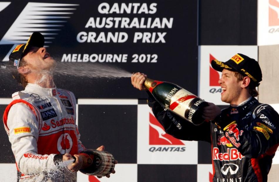 Second-placed driver Sebastian Vettel (R) of Germany sprays champagne on winner Jenson Button of...
