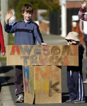Jacob Glossop (11) and his brother, Samuel (5), wave to the trucks as the pass along Queens Dr...