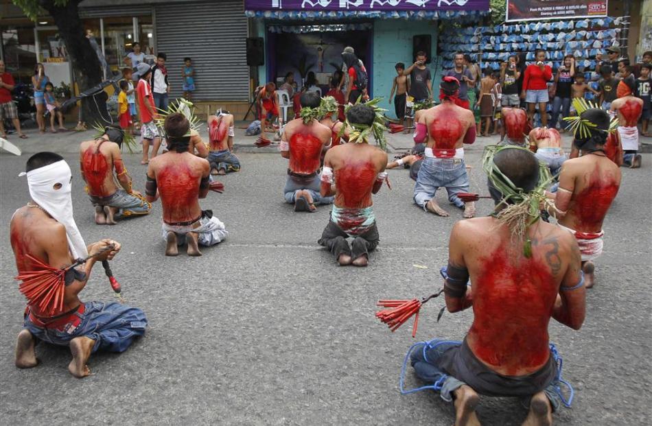 Hooded barefoot penitents perform self-flagellation to atone for their sins in San Fernando,...