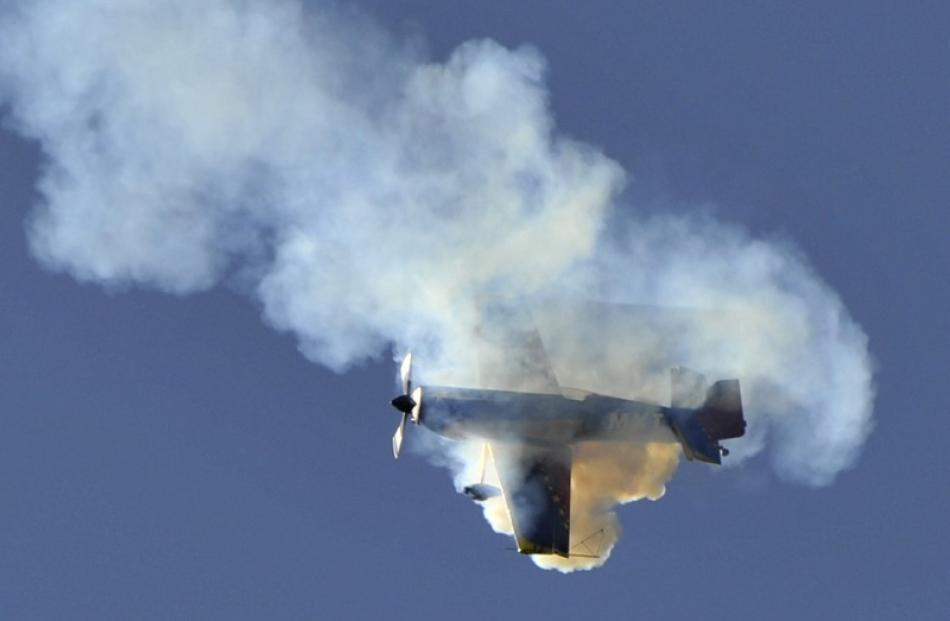 An MX2 aerobatic aircraft, flown by Doug Brooker, is shrouded in smoke as it performs a maneuver...