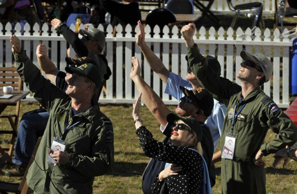 Members of the RNZAF shield themselves from the sun to get a better view of the action during...