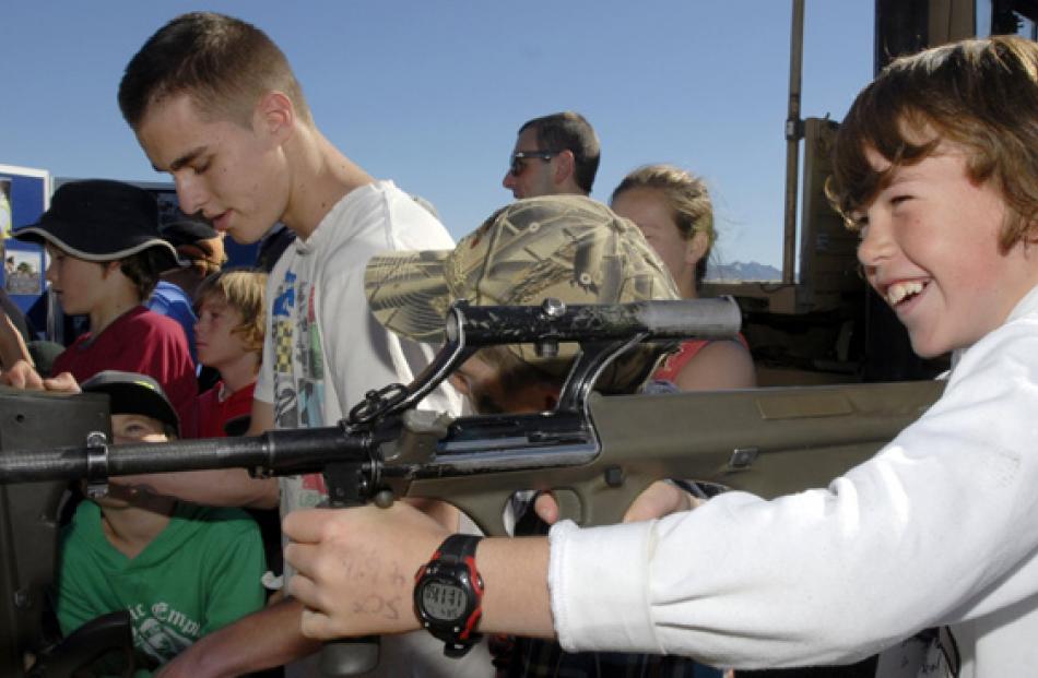 Tate Barron, of Dunedin, tries on a Steyr assault rifle for size at a NZ Defense Force display...