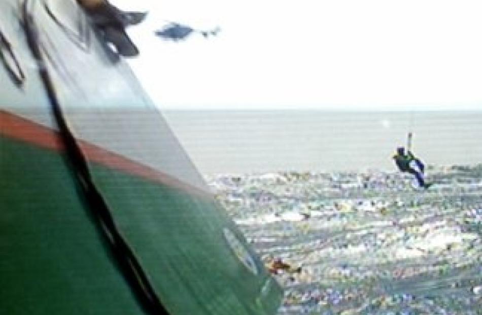 A recuer is lowered towards the sea during the rescue of the trimaran 'Groupama 3'. Photo from...