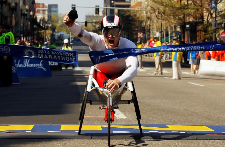 Joshua Cassidy of Canada breaks the tape to win the men's wheelchair division of the 116th Boston...