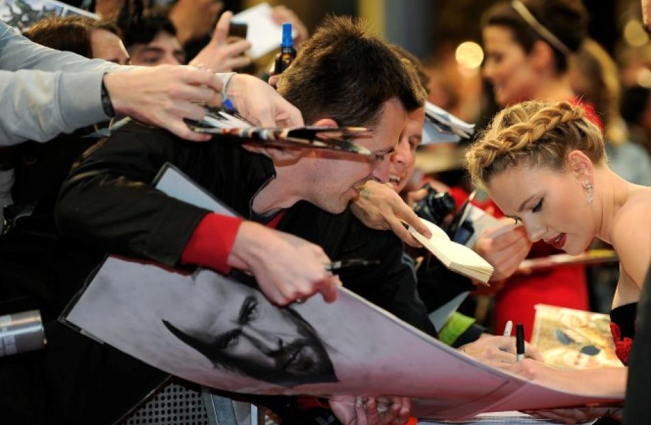 Scarlett Johansson signs autographs for fans as she arrives for the European premiere of Avengers...
