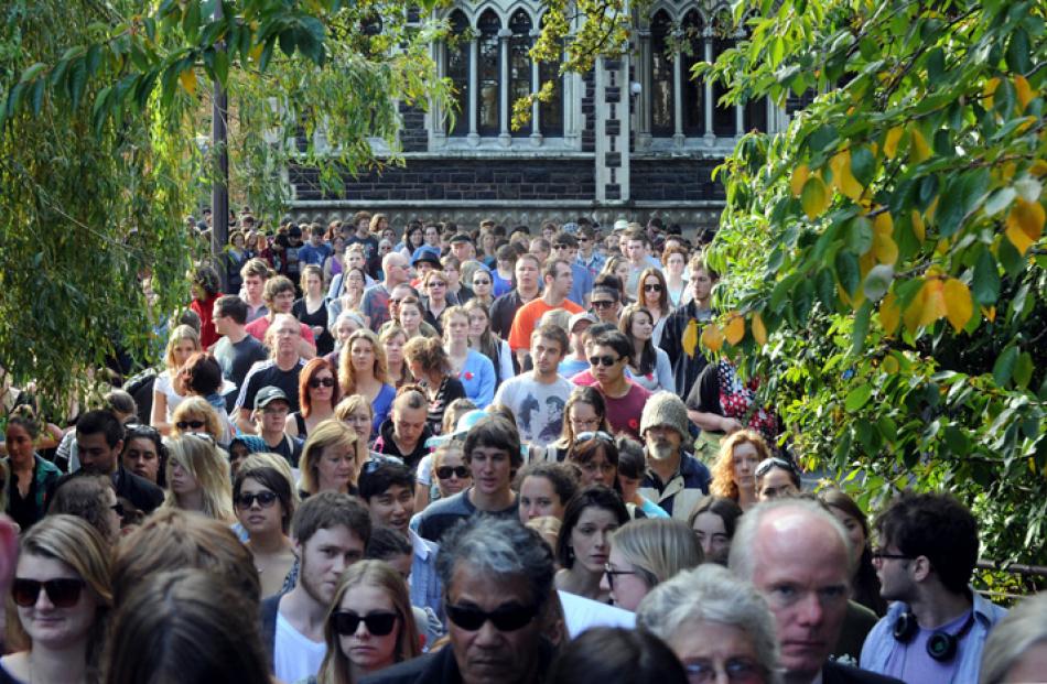 University staff and students parade along Memorial walk past the clocktower