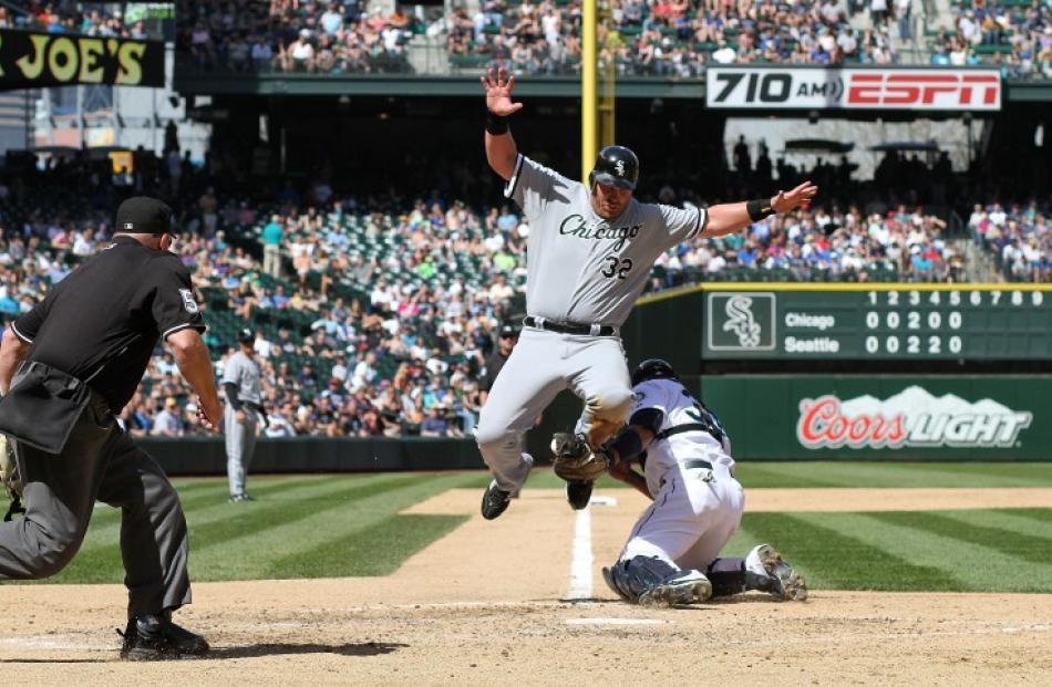 Adam Dunn of the Chicago White Sox leaps but is unable to avoid the tag at home plate by Seattle...