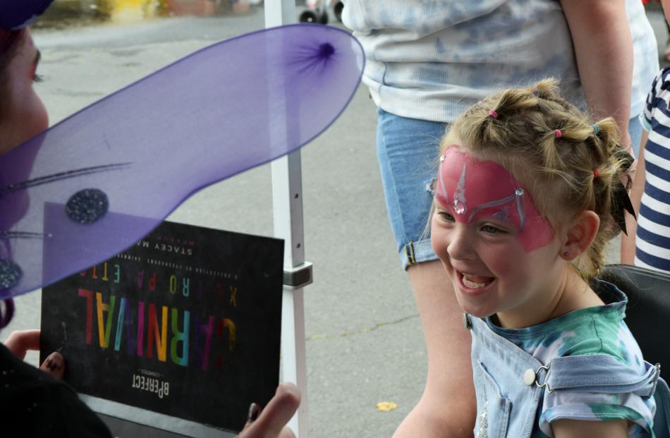 Face painter Mel ‘‘Fairy Spot’’ Hall holds up a mirror to show Isobella Mahon (5), of St Kilda,...