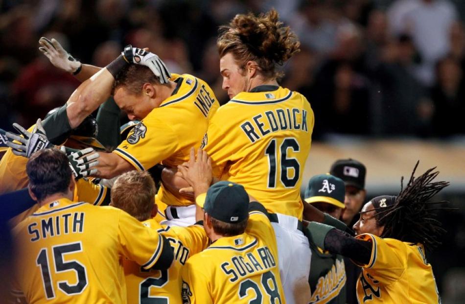 Oakland Athletics baserunner Brandon Inge (top left) is congratulated by teammates after hitting...
