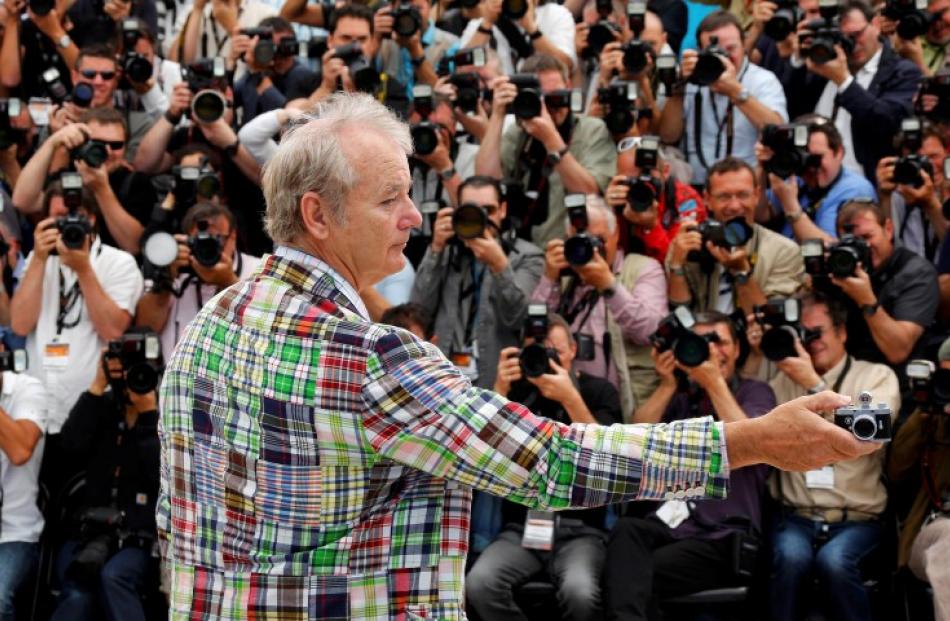 Cast member Bill Murray takes a photograph as he poses during a photocall for the film 'Moonrise...