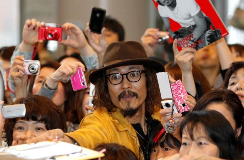 Ken Shimizu, a Japanese Johnny Depp impersonator, reaches out to receive an autograph from the...