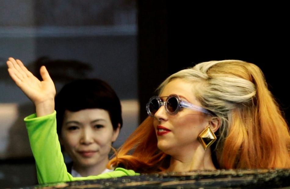 US singer Lady Gaga waves upon her arrival for her concert tour, at Taipei Songshan airport in...