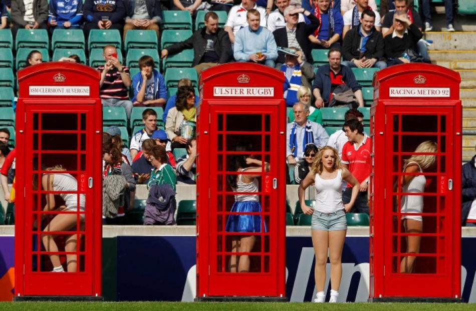 Cheerleaders change their outfits in red phone booths during a performance before the Heineken...