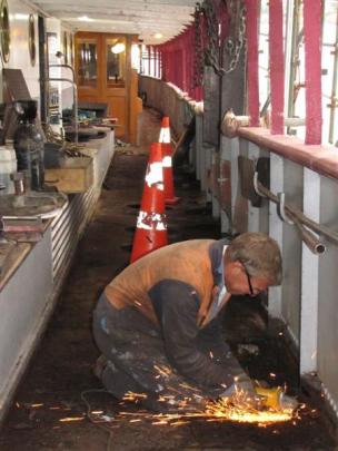 Shipwright Trevor Keogh grinds away rivets which hold in place corroded metal strengthening plates.