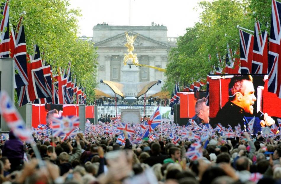 Spectators watch Robbie Williams on giant screens near the palace. REUTERS/Ki Price