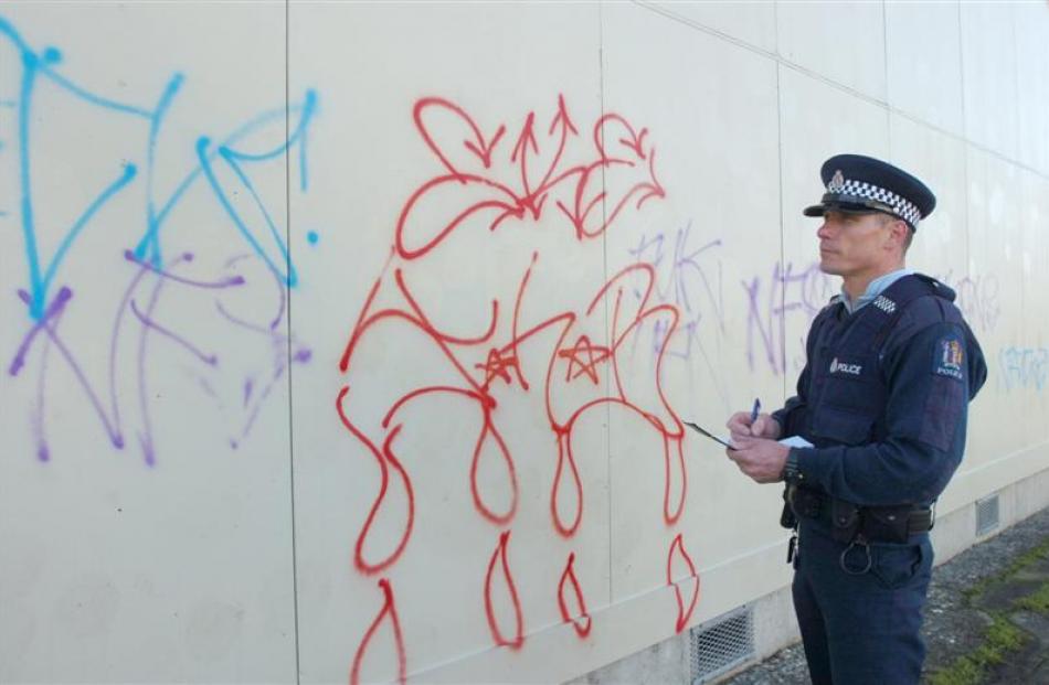 Constable Matthew Stoddard, of South Dunedin, takes notes of graffiti sprayed on to the walls of...