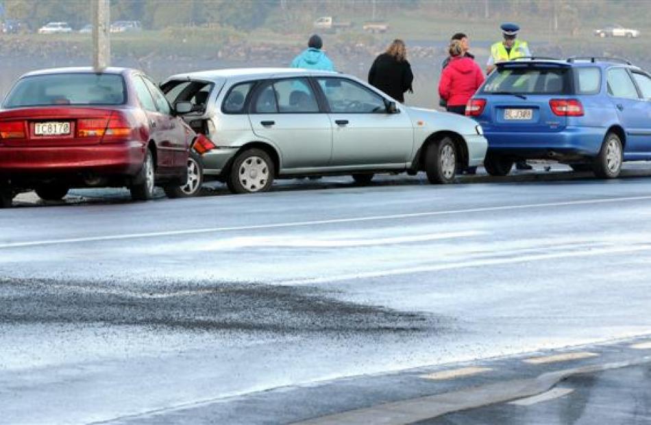 Police talk to witnesses at a black-ice spot where these three cars all separately lost their...