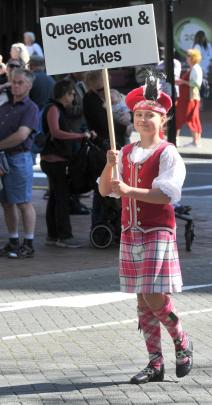 Georgia Dahlenburg (9), of Mosgiel, holds a sign for the Queenstown and Southern Lakes Pipe Band...