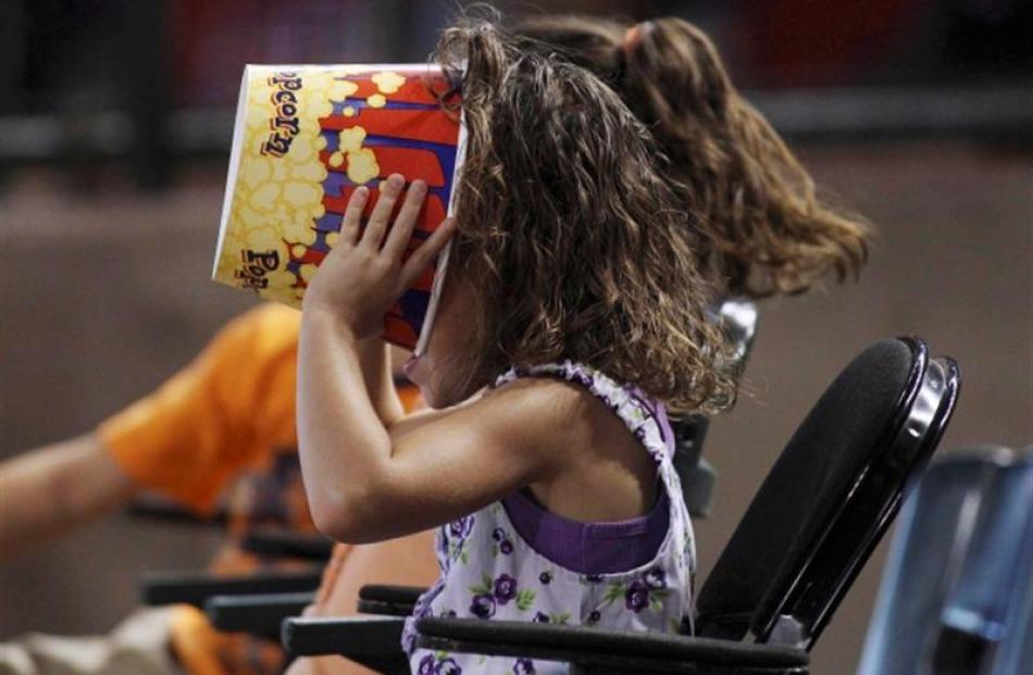 A young baseball fan makes sure there's not a kernel of popcorn left as she watches the Chicago...