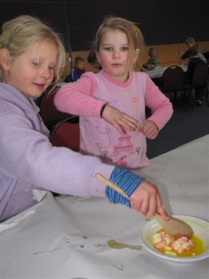 Zoe Sinteur (6), left, begins mixing ingredients for rice-bubble cakes as Caitlin Bowman (5),...