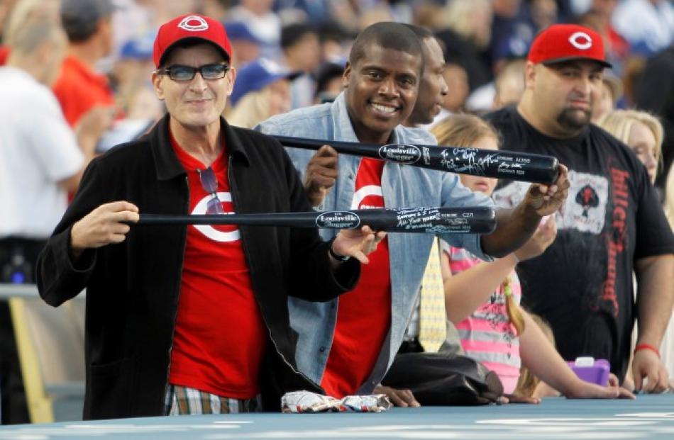 Actor Charlie Sheen (L) and his friend Tony Todd show off bats given to them by players from the...