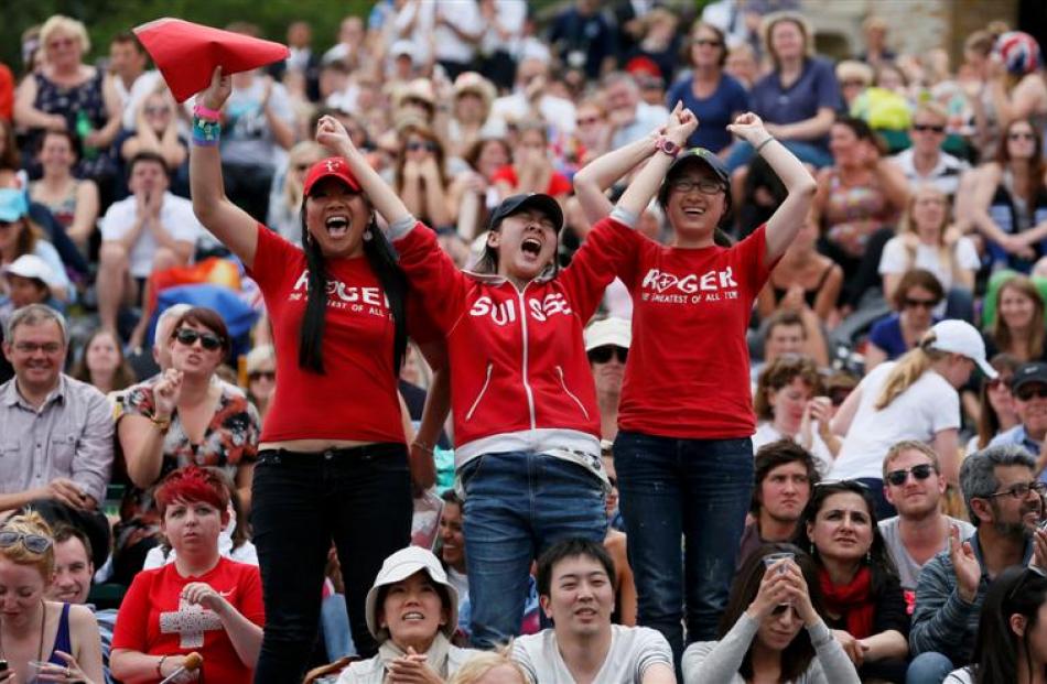 Spectators on Murray Mound (also known as Henman Hill) react to Roger Federer of Switzerland...