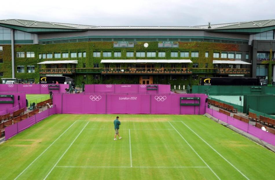 A workman walks across Court 10 as Olympic hoarding is erected at the All England Lawn Tennis...