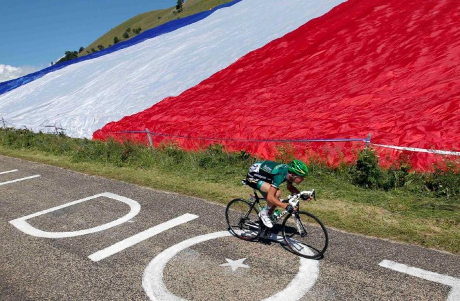 Team Europcar rider Thomas Voeckler of France cycles past a giant French flag during the 10th...