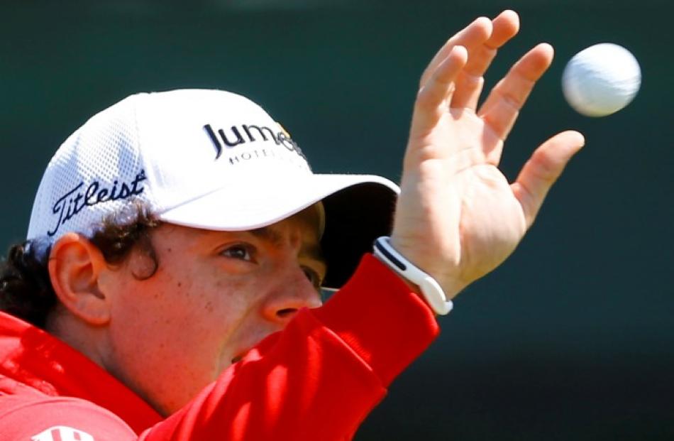Rory McIlroy of Northern Ireland catches a ball on the driving range during a practice round for...