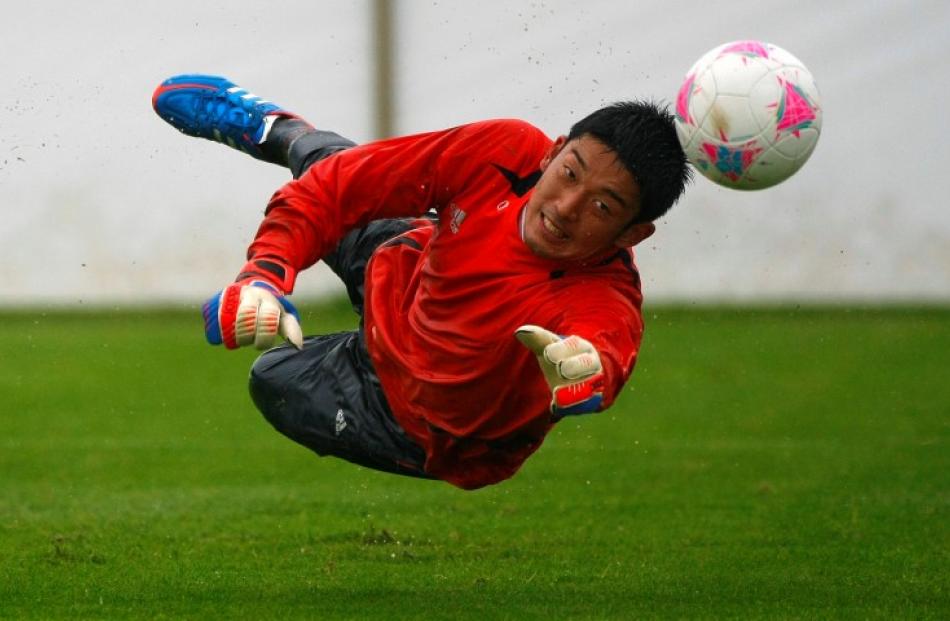Japan goalkeeper Shuichi Gonda dives to block a shot at a goal during an Olympics training...