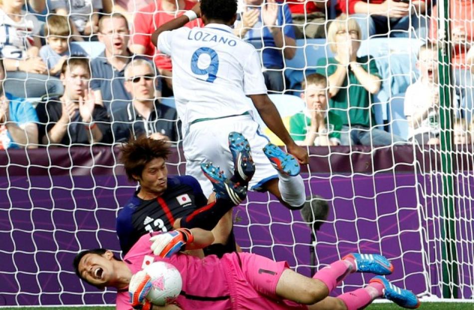 Japan's Daisuke Suzuki (13) falls on his goalkeeper Shuichi Gonda near Honduras' Antony Lozano in...