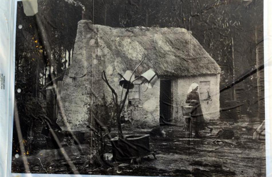A European settler woman is pictured outside a wattle and daub cottage  in 19th century Otago....