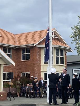 Members of the HMNZS Toroa flag party lower the New Zealand flag in preparation for raising the...