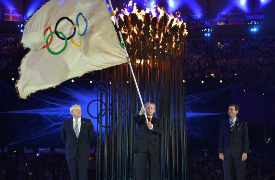 IOC President Jacques Rogge holds the Olympic flag after receiving it from London Mayor Boris...