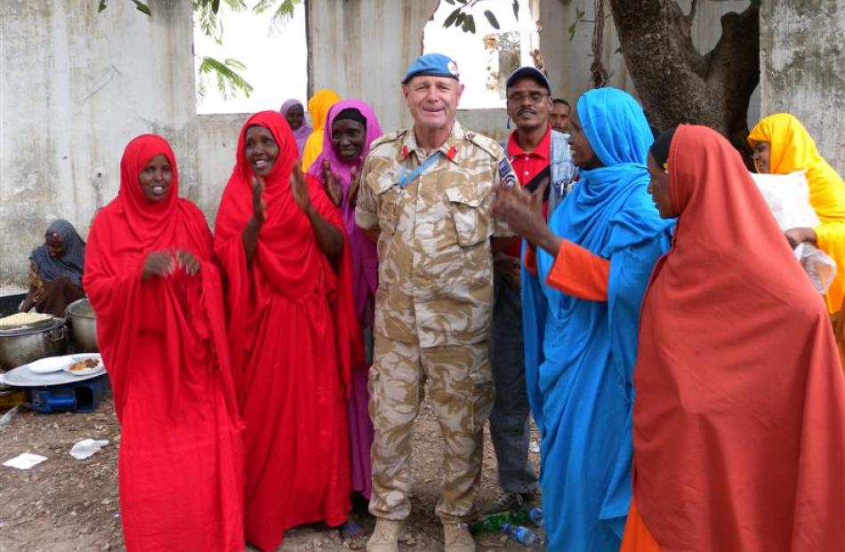 Col Howie with a group of Somali women in bright traditional robes.