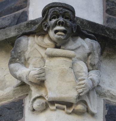 A jovial figure holds an unfurled scroll from before the age of print.