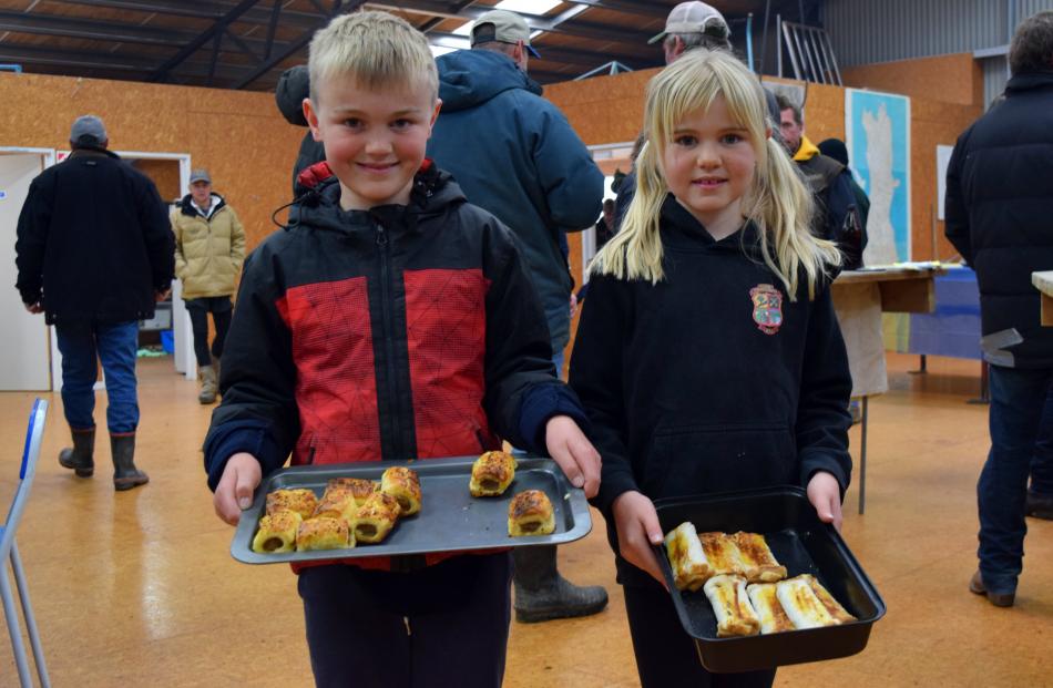 Siblings Blake (9) and Holly (8) Campbell serve snacks to people as the auction runs in the...