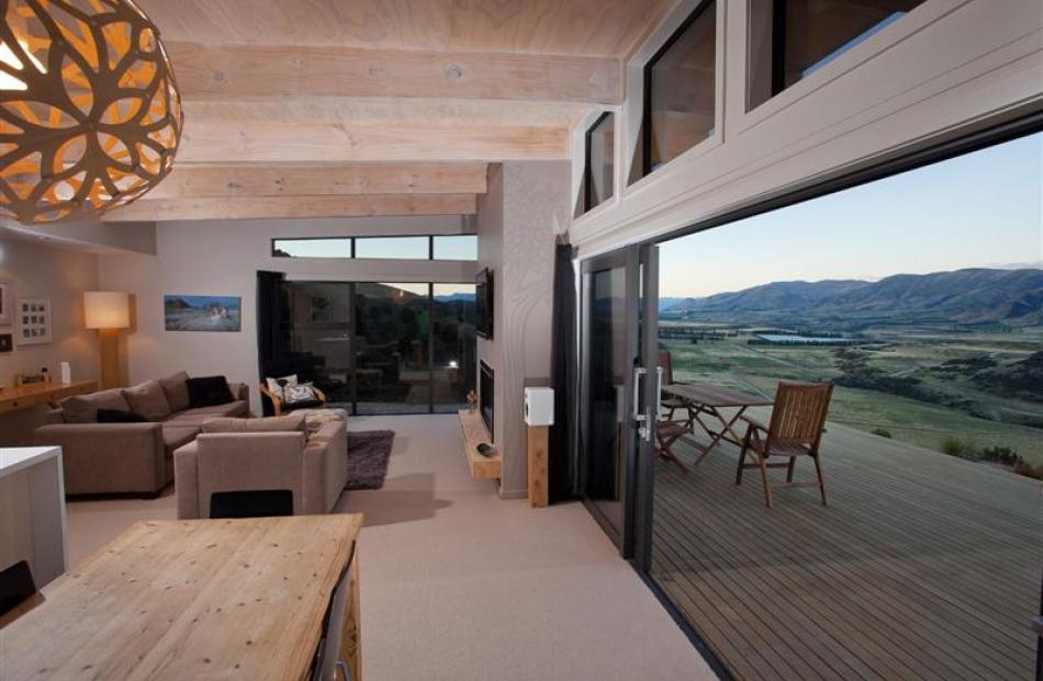 Large expanses of glass capture views of the Clutha River basin and decks hover in the landscape....