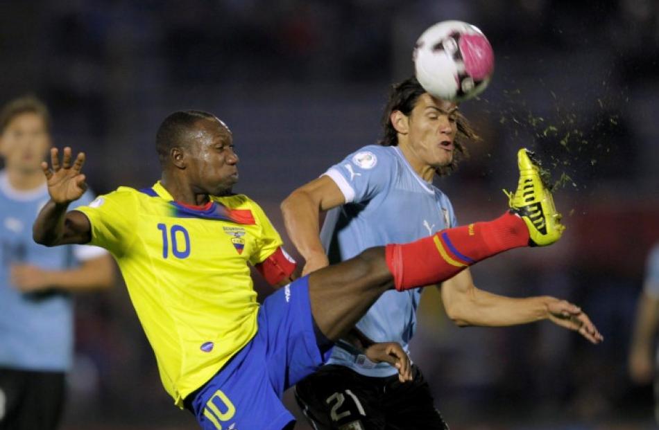 Ecuador's Walter Ayovi (L) fights for the ball with Uruguay's Edinson Cavani during their 2014...