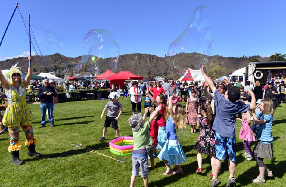 Children chase giant bubbles in Pioneer Park.