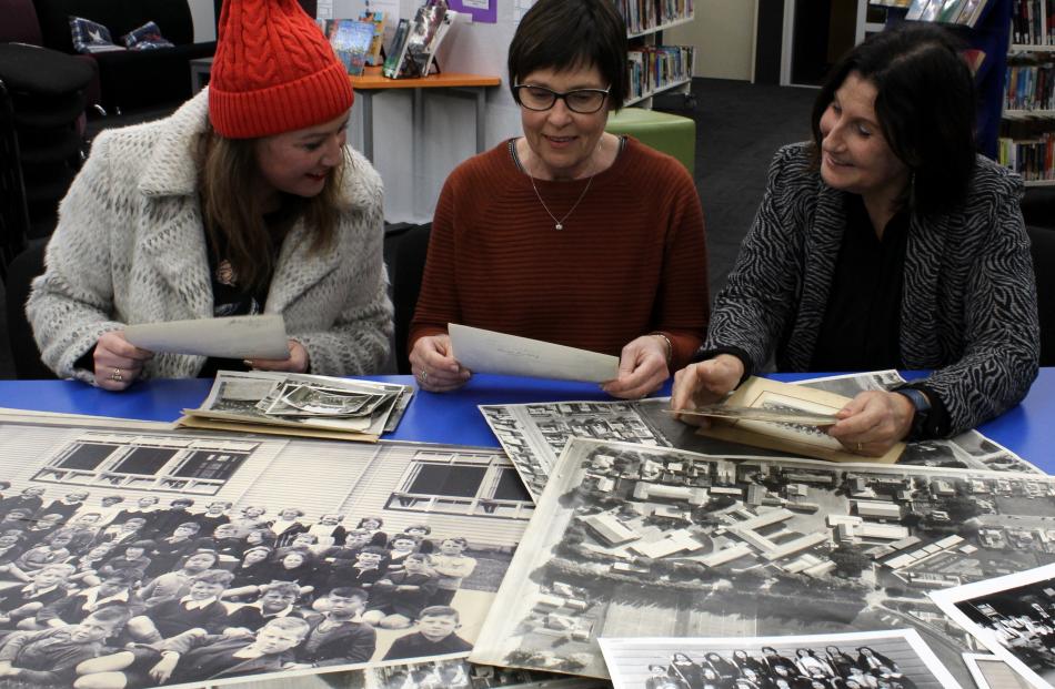 Poring over archive photos at the Taieri College library are Taieri College reunion committee...