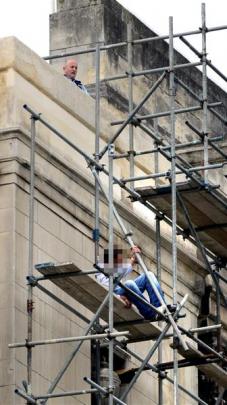 Senior Constable Mal Parker peers from the Dunedin Town Hall roof at a man on scaffolding yesterday.