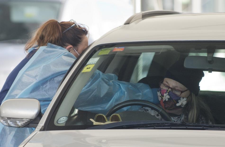 A health worker reaches inside a car to administer a vaccination.
