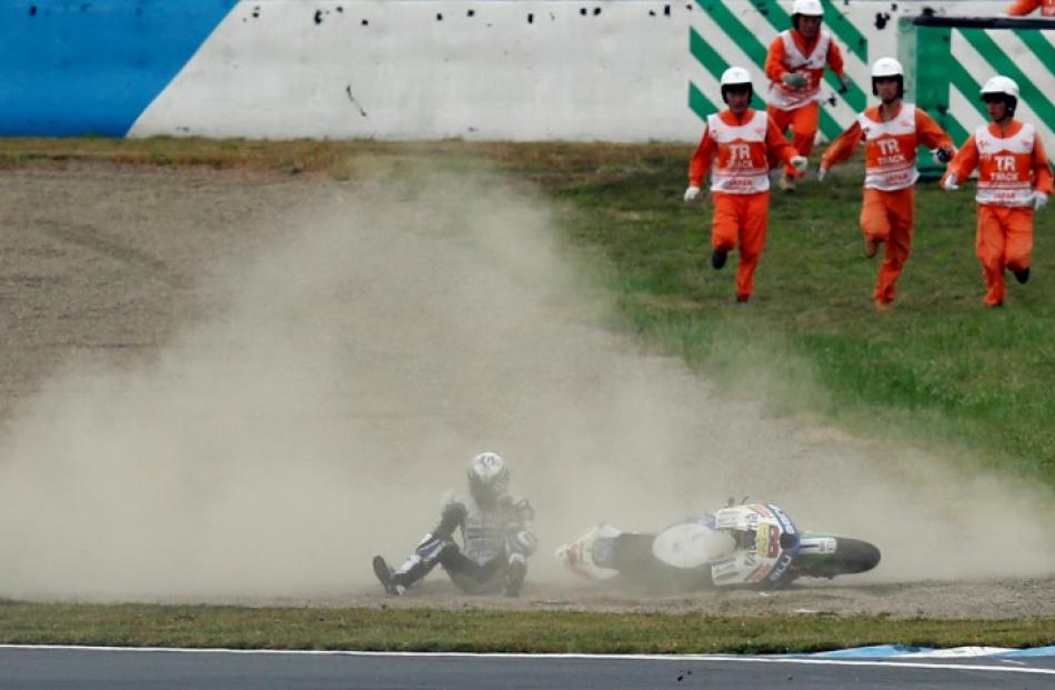 Course marshals run towards Colombian rider Yonny Hernandez after he fell off his motorcycle...