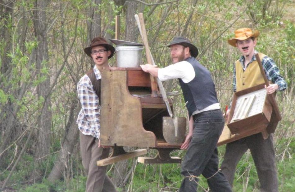 Actors in the re-enactment of the discovery of gold move a sluice to the Arrow River on Saturday....